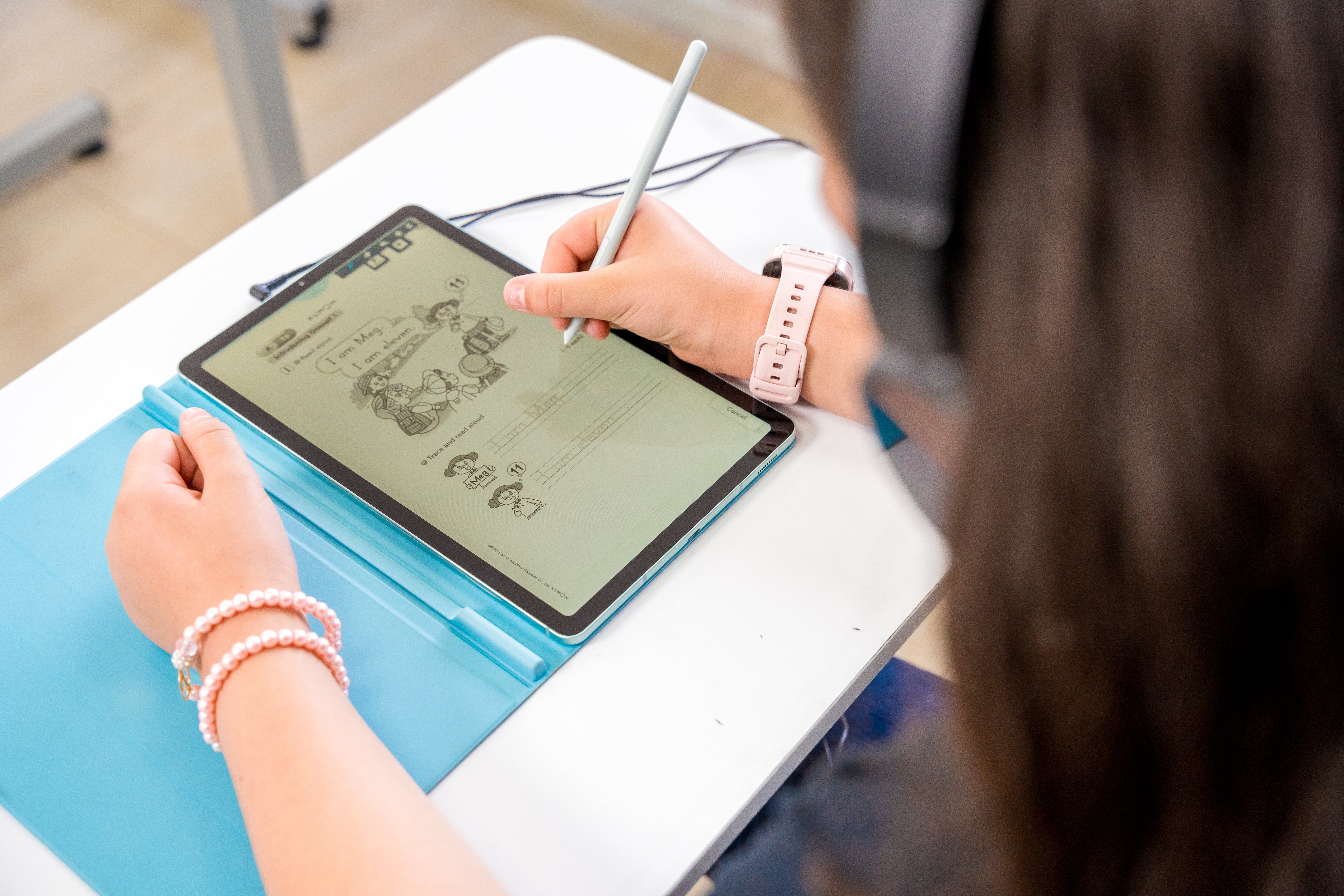 Estudiante practicando inglés en una tableta con ejercicios Kumon, usando auriculares para mejorar su aprendizaje.
