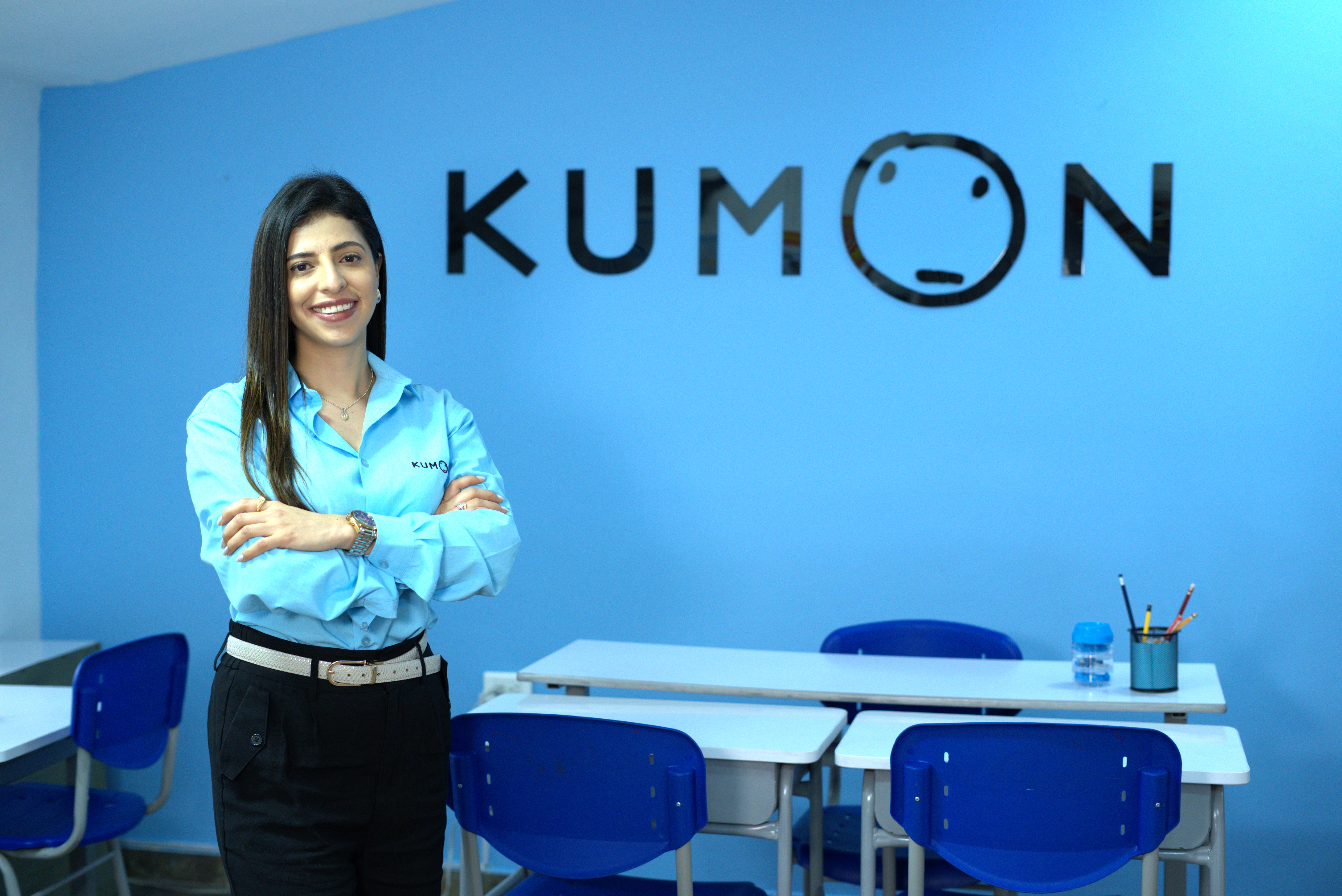 Orientadora de Kumon con los brazos cruzados y postura de emprendedora, de pie, sonriendo y feliz por la apertura de su nuevo centro