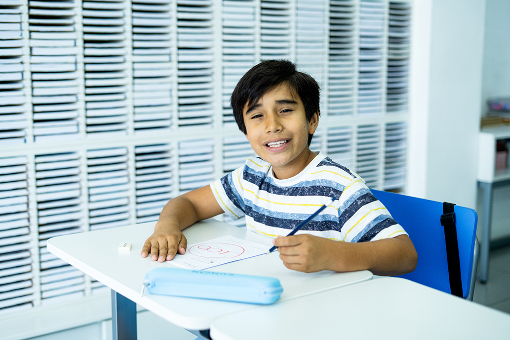 Alumno sentado, sosteniendo un lápiz y sonriendo en el aula de un centro Kumon-Argentina