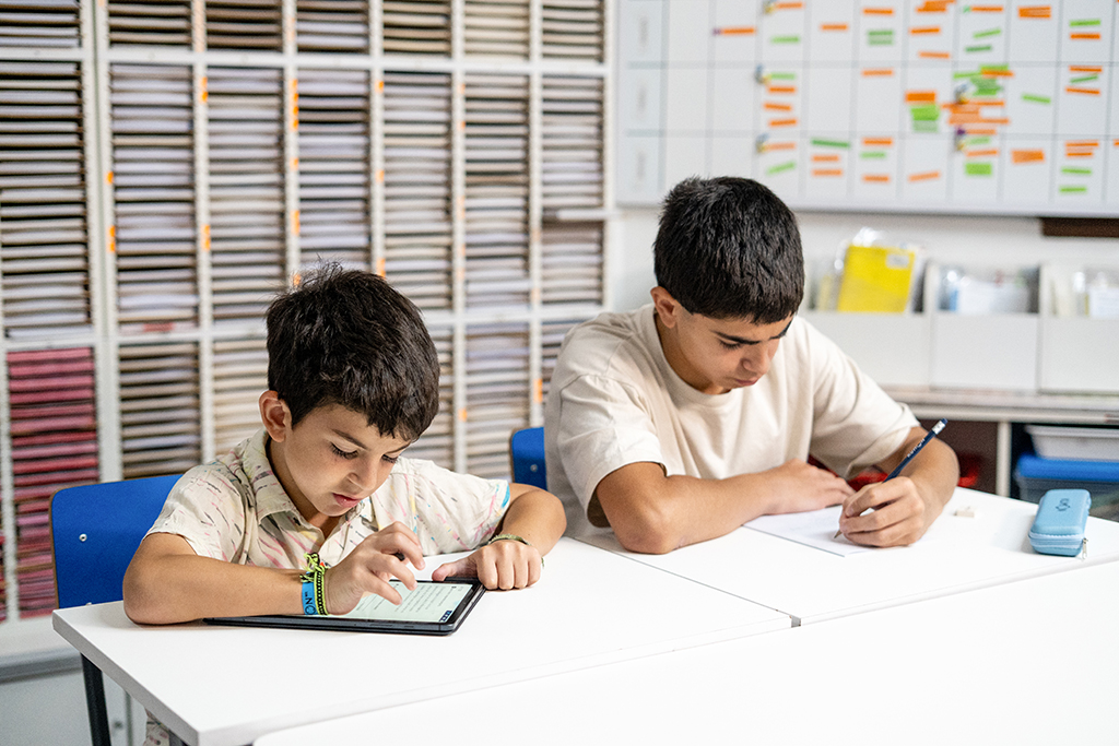 Dos estudiantes en un aula de Kumon, uno trabajando en una tableta y otro escribiendo en papel-Argentina