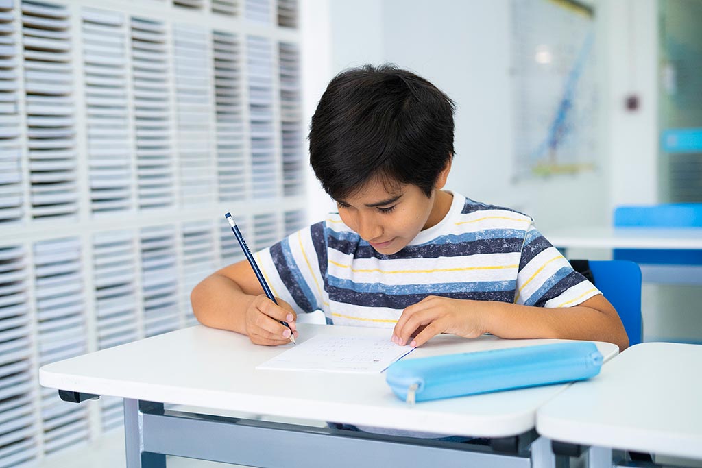 Niño concentrado resolviendo ejercicios en papel como parte del método de estudio individualizado de Kumon-Argentina