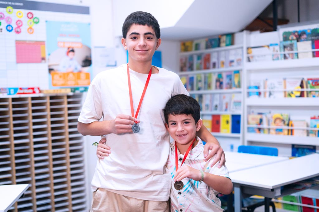 Dos estudiantes en un centro Kumon mostrando orgullosamente sus medallas por logros educativos-Argentina