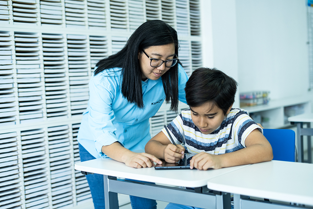 Orientador guiando a un estudiante mientras utiliza una tableta para el aprendizaje individualizado en el aula-Argentina